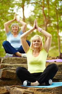 Portrait of two aged females practicing yoga in park